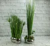 Two artificial plants in silver ceramic pots against a white brick wall. Podgląd zdjęcia produktu