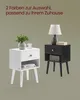 Two nightstands, one white and one black, are displayed side-by-side against a neutral background. The white nightstand has a plant and a candle on top, while the black nightstand has a lamp and books. Both nightstands feature a drawer and an open shelf. Produktbild-Vorschau