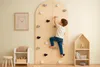A young boy is climbing a wooden climbing wall in a child's room. There is a framed picture of a bear on the wall and a small wooden shelf with toys. Voir les images du produit