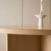 A close-up of a wooden table with a candle holder and lit candle in the background. Voir les images du produit