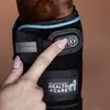 A close-up shot of a person's hand touching a horse's leg boot. Podgląd zdjęcia produktu