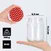 A hand holds a red and white polka dot lid above a clear glass jar, with measurement indicators and icons for weight and diameter shown. Voir les images du produit
