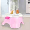 A child's legs are shown standing on a pink and white potty training seat in a bathroom. Produktbild-Vorschau
