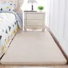 A fluffy beige rug is placed on the floor next to a bed with geometric patterned bedding and a white nightstand. Podgląd zdjęcia produktu