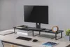 A desk setup with a monitor stand holding a monitor, books, and a clock. Náhled obrázku produktu