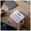 A person is using a Brother P-touch D410 label maker to label a red cable connected to a laptop. Produktbild-Vorschau