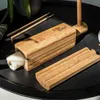 A bamboo sushi-making set is shown on a black tray with chopsticks and a partially made sushi roll. Náhľad obrázku produktu