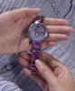 Hands holding a purple and silver Guess watch with a decorative face. Náhled obrázku produktu