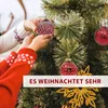 Hands decorating a Christmas tree with red ornaments. Produktbild-Vorschau
