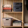 Shelving unit with storage baskets and folded clothes. Produktbild-Vorschau