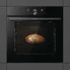 A black oven with a loaf of bread baking inside. Produktbild-Vorschau