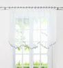 A sheer white curtain with a scalloped hem and a gray trim hangs in front of a window. Produktbild-Vorschau