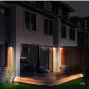 Solarbetriebene Wandleuchten und Bodenleuchten beleuchten nachts die Terrasse eines modernen Hauses Náhľad obrázku produktu
