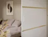 A sliding door with gold accents is shown in the foreground, with a living room scene including a sofa and artwork blurred in the background. Produktbild-Vorschau