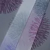 A close-up view of a fabric with a repeating pattern of stylized fireworks in purple and gray. Produktbild-Vorschau