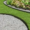A garden scene showing black landscape edging separating a lawn from a flower bed and a gravel path. Produktbild-Vorschau