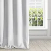 A white curtain is shown partially covering a window with greenery visible outside. The floor is made of light-colored wood planks. Produktbild-Vorschau