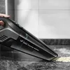 A hand holding a black handheld vacuum cleaner, cleaning up dust and debris from a countertop. Podgląd zdjęcia produktu