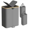 A grey laundry basket with a wooden rim and a divided lid is shown, along with two smaller grey laundry bags. Produktbild-Vorschau