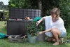 A woman is tending to plants in a garden next to a large storage box. Anteprima dell’immagine prodotto