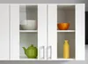 A close-up view of a white kitchen cabinet with glass doors, showcasing various kitchenware items on shelves. Náhled obrázku produktu