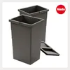 Two dark gray trash bins are shown side-by-side on a white background. A small gray lid is placed in front of the bins. Produktbild-Vorschau