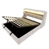 A beige upholstered bed frame with the mattress support mechanism lifted to reveal storage space underneath. The headboard has integrated lighting and shelving. Náhled obrázku produktu