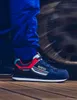 A person wearing blue pants and a blue Sparco Gymkhana Martini racing shoe, with a blurred tire in the background. Podgląd zdjęcia produktu