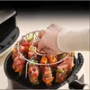 A hand is shown placing skewers of meat and vegetables into a circular rack inside an air fryer. Náhľad obrázku produktu