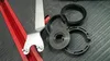 A close-up view of various parts of an angle grinder dust extraction cover, along with a metal wrench, laid out on a textured black surface. Náhled obrázku produktu