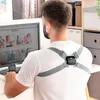 A man is sitting at a desk, looking at a computer screen, while wearing a posture corrector device. Podgląd zdjęcia produktu