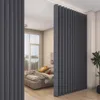 A bedroom with a bed and a dark gray room divider. Náhled obrázku produktu