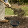 A person is using a sieve to sift soil in a garden. Anteprima dell’immagine prodotto