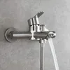 A close-up shot of a stainless steel shower faucet mounted on a gray tiled wall, with water flowing from the spout. Produktbild-Vorschau