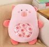 A pink plush toy with smaller plush toys inside is sitting on a textured surface, with books in the background. Anteprima dell’immagine prodotto