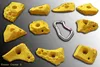 Set von gelben Klettergriffen "Erosion Cracker S" von Move-it-Climbingholds; umgeben von einem Karabiner. Produktbild-Vorschau
