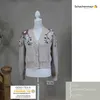 A beige cardigan with floral embroidery displayed on a mannequin. Produktbild-Vorschau