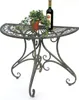 A half-round metal table with decorative scrollwork, holding a potted plant and a bottle of wine. Produktbild-Vorschau