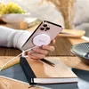 A person is holding a smartphone with a wireless charger attached, on a table with a notebook and pen. Anteprima dell’immagine prodotto