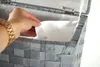 A hand is reaching into a grey woven laundry basket with a white lining. Podgląd zdjęcia produktu