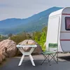 A white folding table with food on it and a green camping chair next to a caravan, with mountains in the background. Anteprima dell’immagine prodotto