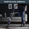 A person is using a cordless vacuum cleaner in a modern living room. Produktbild-Vorschau