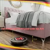 A robot vacuum cleaner is shown cleaning under a pink upholstered bed. The bed has a tufted headboard and is covered with a gray blanket. A measurement of 12cm is indicated. Produktbild-Vorschau