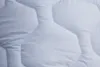 A close-up view of a white quilted blanket. Náhled obrázku produktu