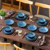 A dining table set with blue stoneware dishes, cutlery, and glasses, arranged for a meal. Náhled obrázku produktu