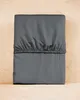 A folded gray fitted sheet is laid flat on a light wood surface. Náhled obrázku produktu