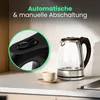 A glass electric kettle with a stainless steel base and a black handle sits on a kitchen counter next to a small cup of coffee. A close-up inset shows the kettle's power switch. Produktbild-Vorschau