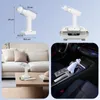 Collage showing a white portable vacuum cleaner in different settings: with dimension labels, on a charging base, on a coffee table, and in a car's cup holder. Produktbild-Vorschau