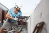 A construction worker is drilling into a concrete wall. Anteprima dell’immagine prodotto