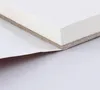 A close-up view of the edge of a block of watercolor paper, showing its layered construction and a partially peeled protective sheet. Podgląd zdjęcia produktu
